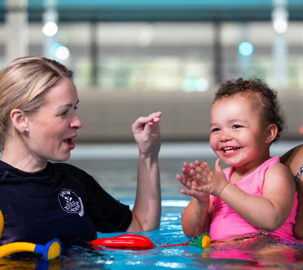 baby in swimming lesson with instructor